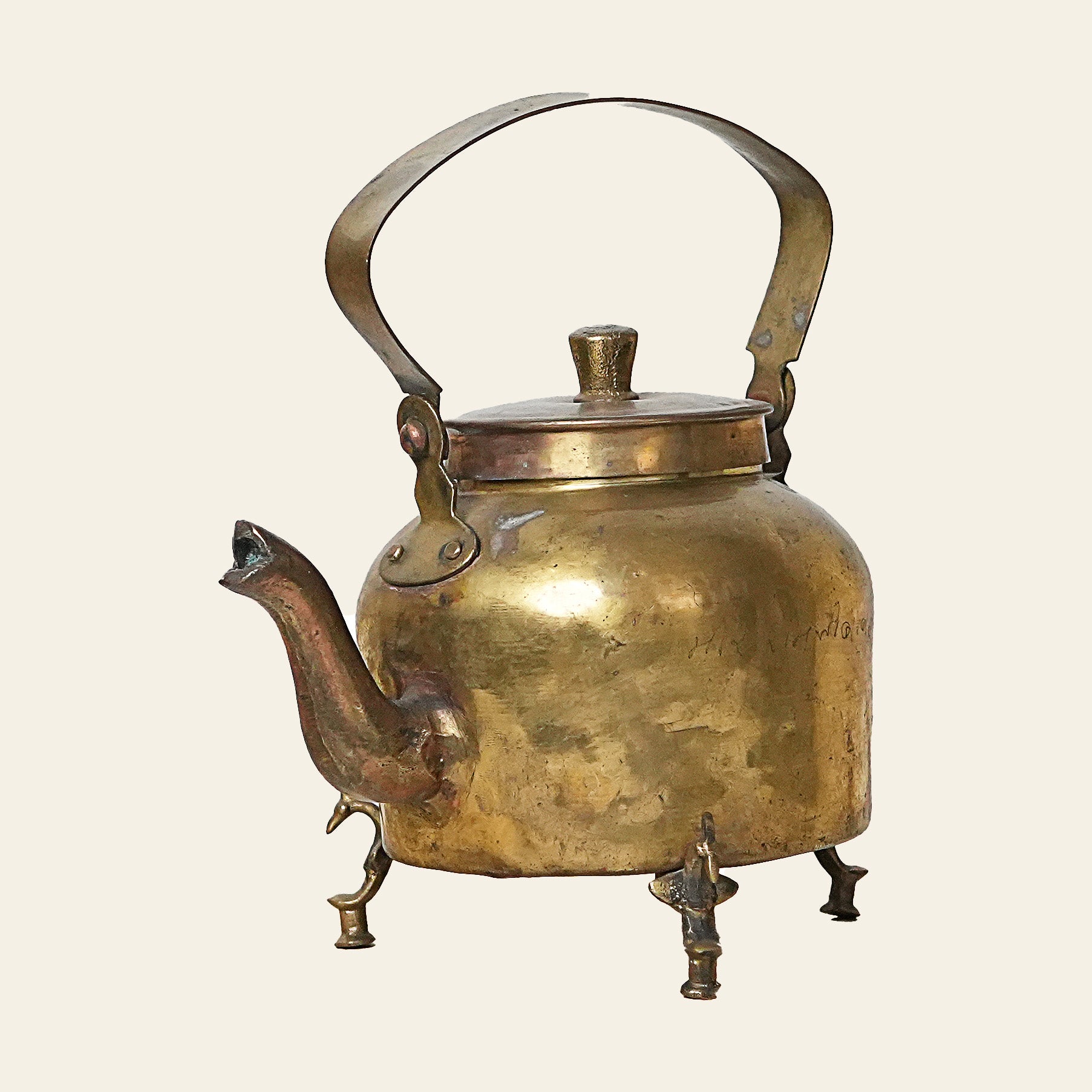 Authentic vintage brass teapot with ornate handle and tripod legs.